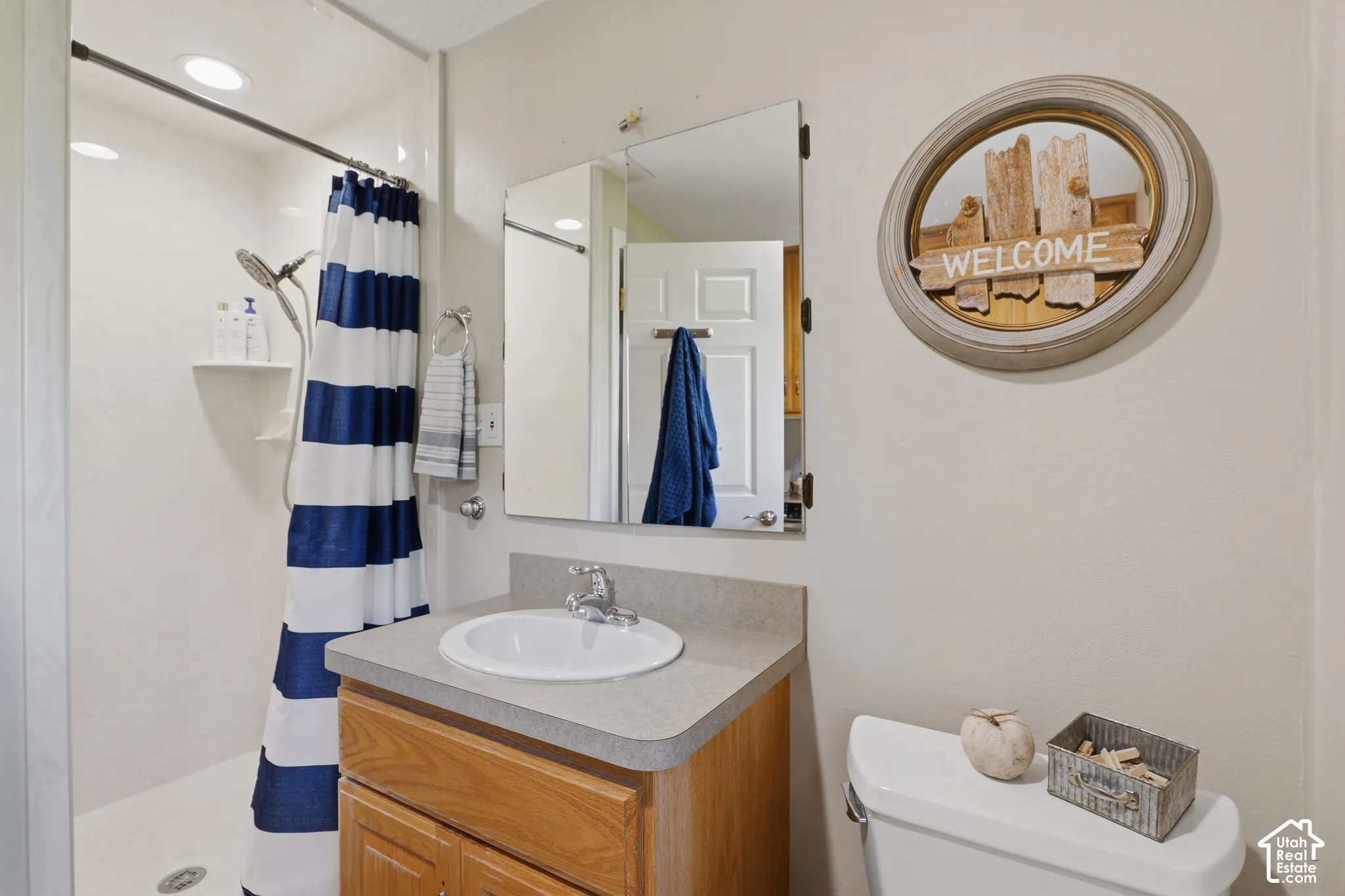 Integrated shower with recessed lighting, single vanity with wood-finish cabinetry, countertop with integrated sink, and wall-mounted medicine cabinet