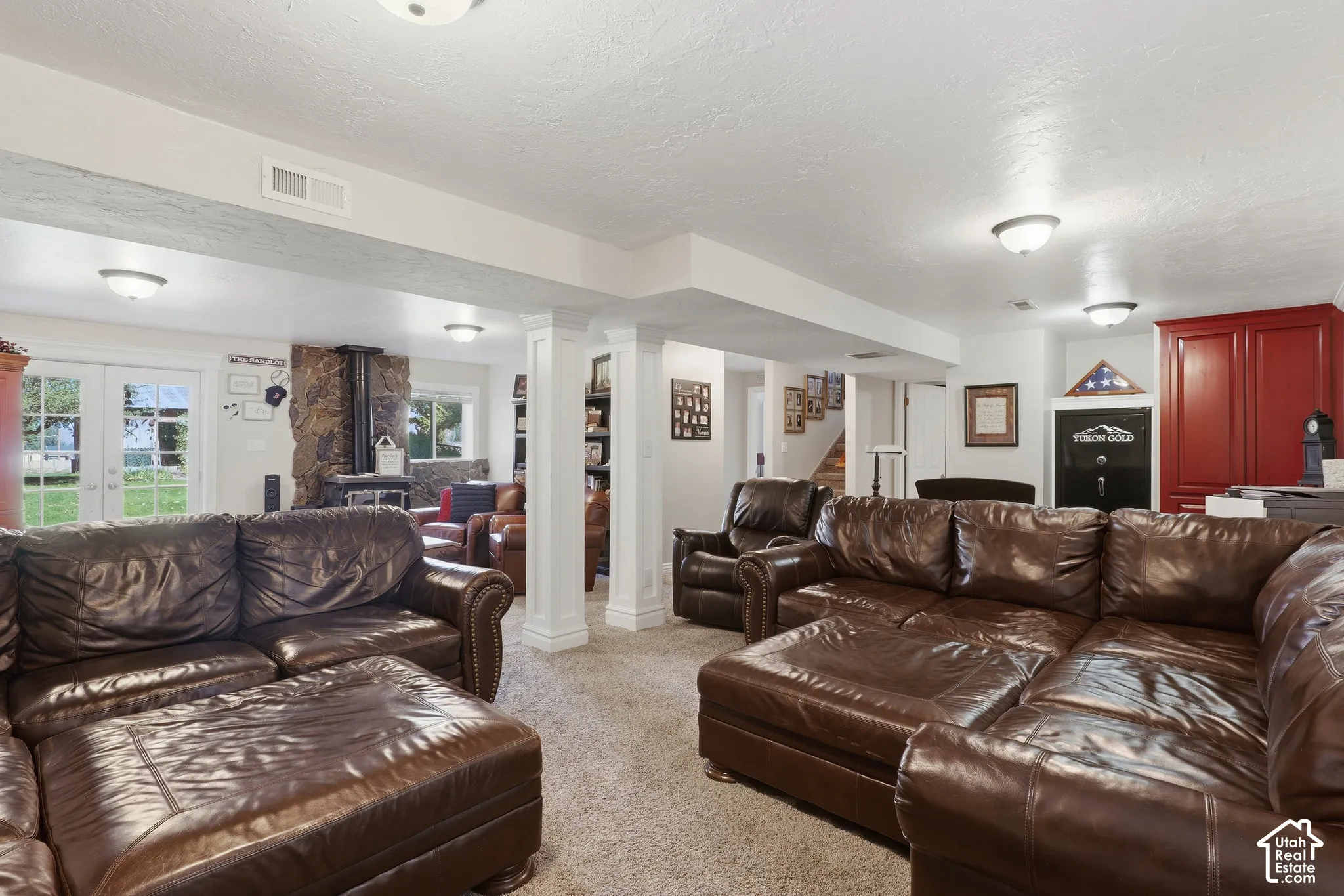 Expansive finished basement with carpet flooring, exposed support columns, and recessed lighting