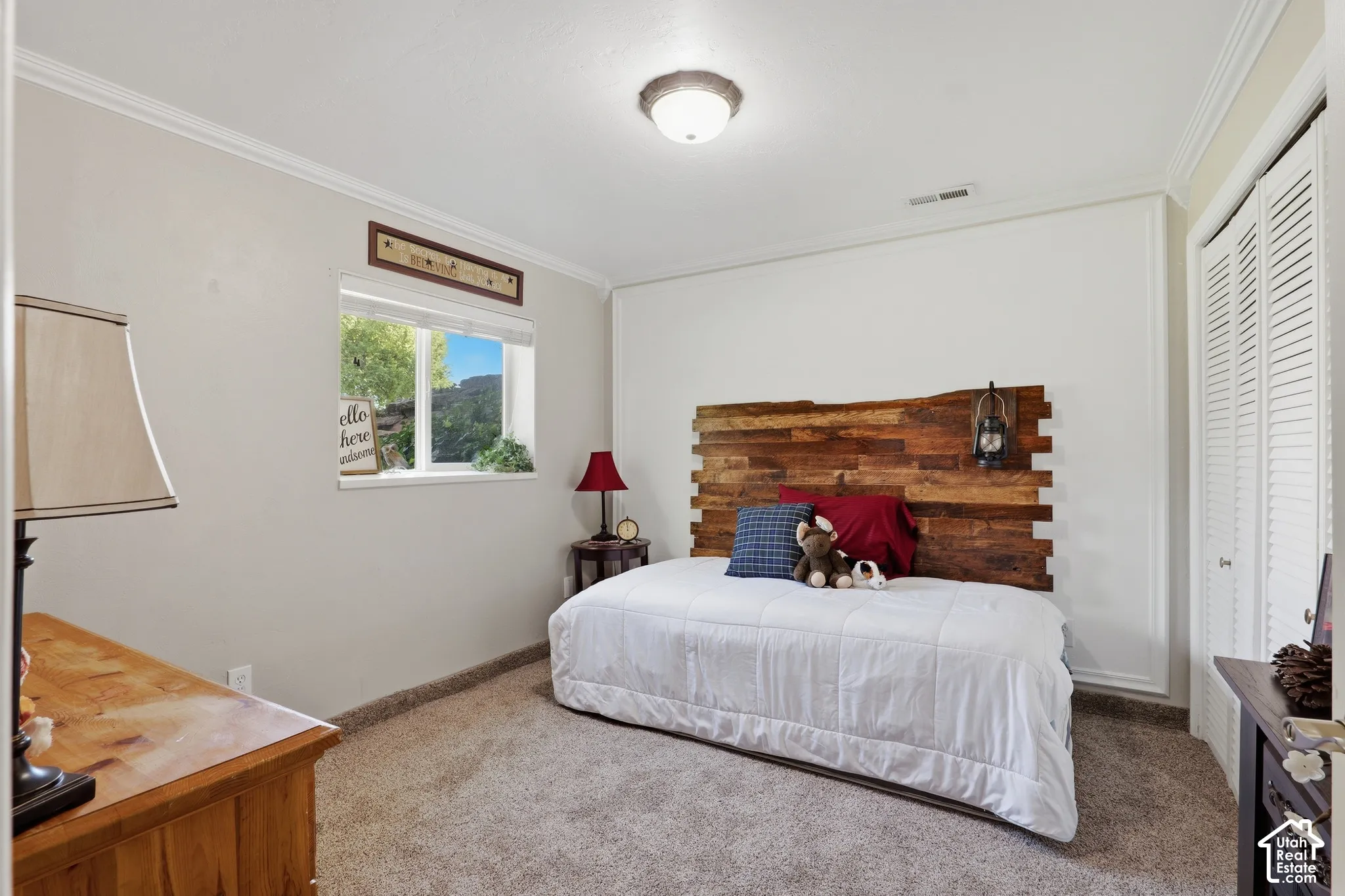 Recessed window with exterior scenery, crown molding, wall-to-wall carpeting, wood-paneled accent wall, and louvered bi-fold closet doors