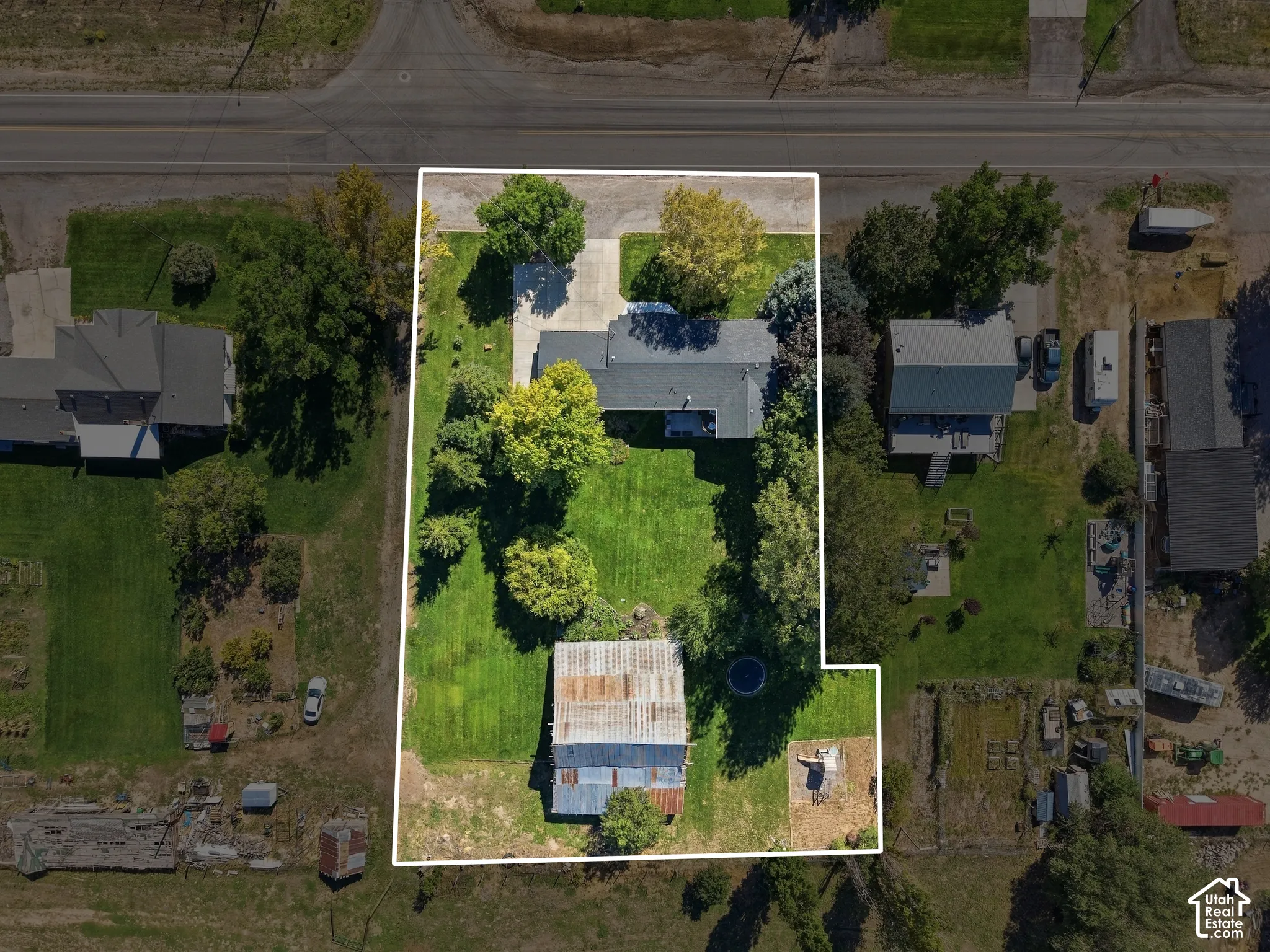 Expansive property featuring a main residence, detached outbuilding, mature trees, and a substantial lawn area