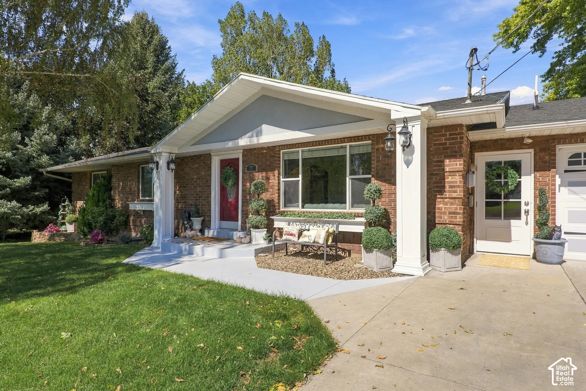 Brick exterior with white trim, covered entry, and expansive front lawn