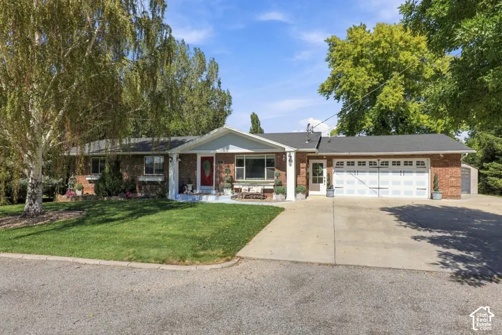 Brick facade with white trim, attached two-car garage, concrete driveway, and front lawn