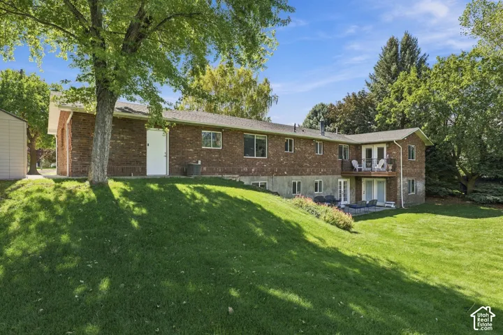 Brick exterior with multiple windows and a lower-level patio