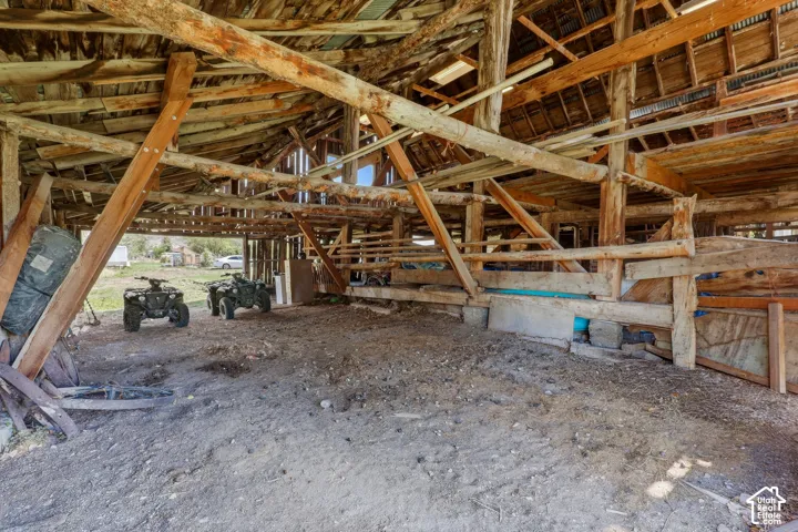 Exposed wood beam construction with a corrugated metal roof and dirt flooring