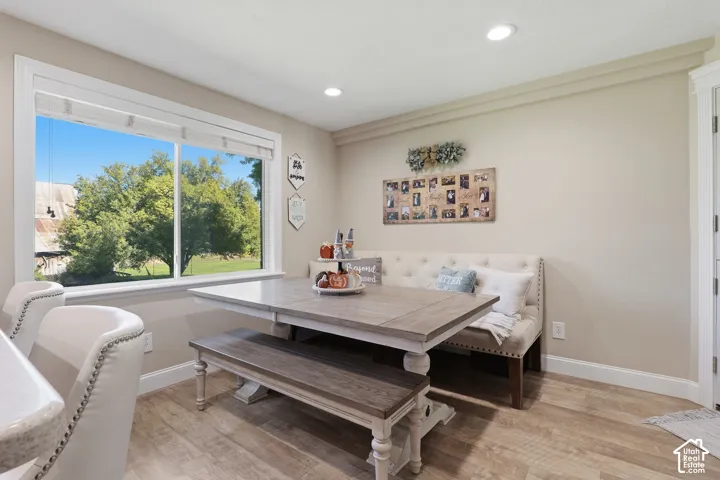 Large window with natural light, recessed ceiling lighting, wood-finish flooring, white trim, and built-in cabinetry