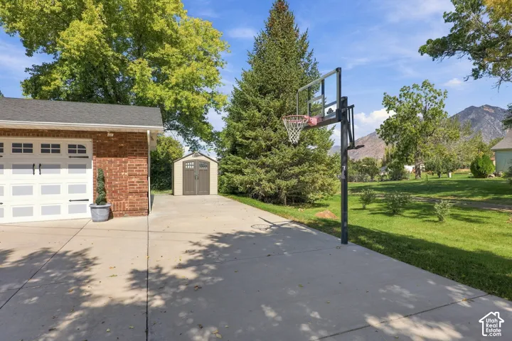 Attached two-car garage with white paneled doors, red brick exterior, concrete driveway, and a detached storage shed
