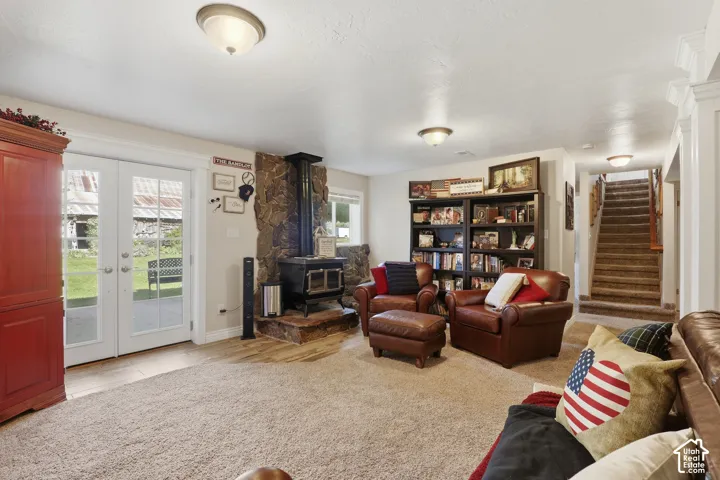 Stone-clad wood-burning stove, white French doors, built-in shelving, carpeted staircase, and wood-finish flooring