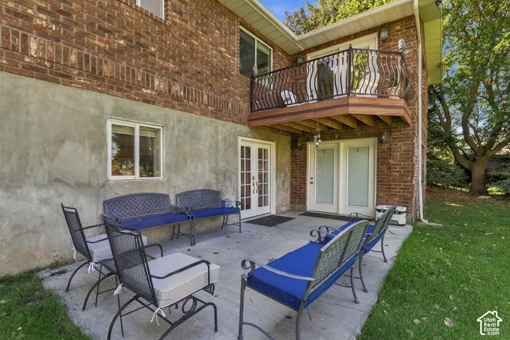 Brick exterior with a ground-level patio and upper-level balcony featuring decorative metal railings