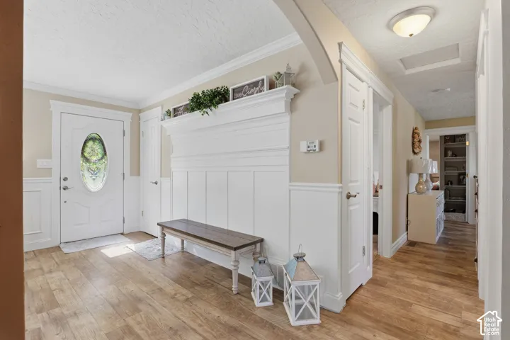 Entryway featuring wood-finish flooring, white wainscoting, and an ornate white mantel