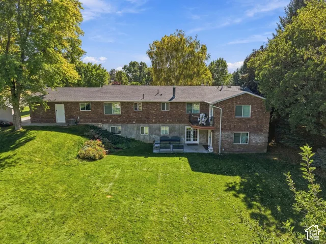 Brick exterior with multiple windows, a second-story balcony, and a ground-level patio