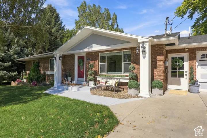 Brick exterior with white trim, covered entry, and expansive front lawn