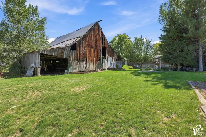 Expansive lawn area with mature trees and a rustic barn structure