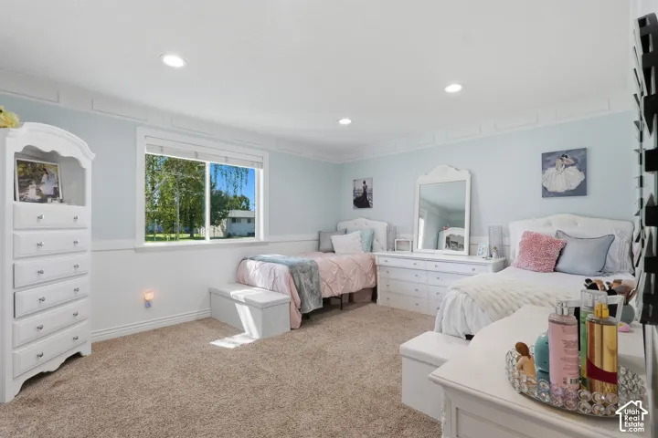 Recessed lighting illuminates a space featuring carpet flooring, horizontal plank wainscoting, and crown molding