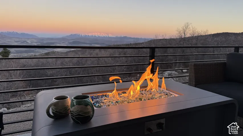 Outdoor gas fire pit with decorative fire glass, surrounded by a black metal railing