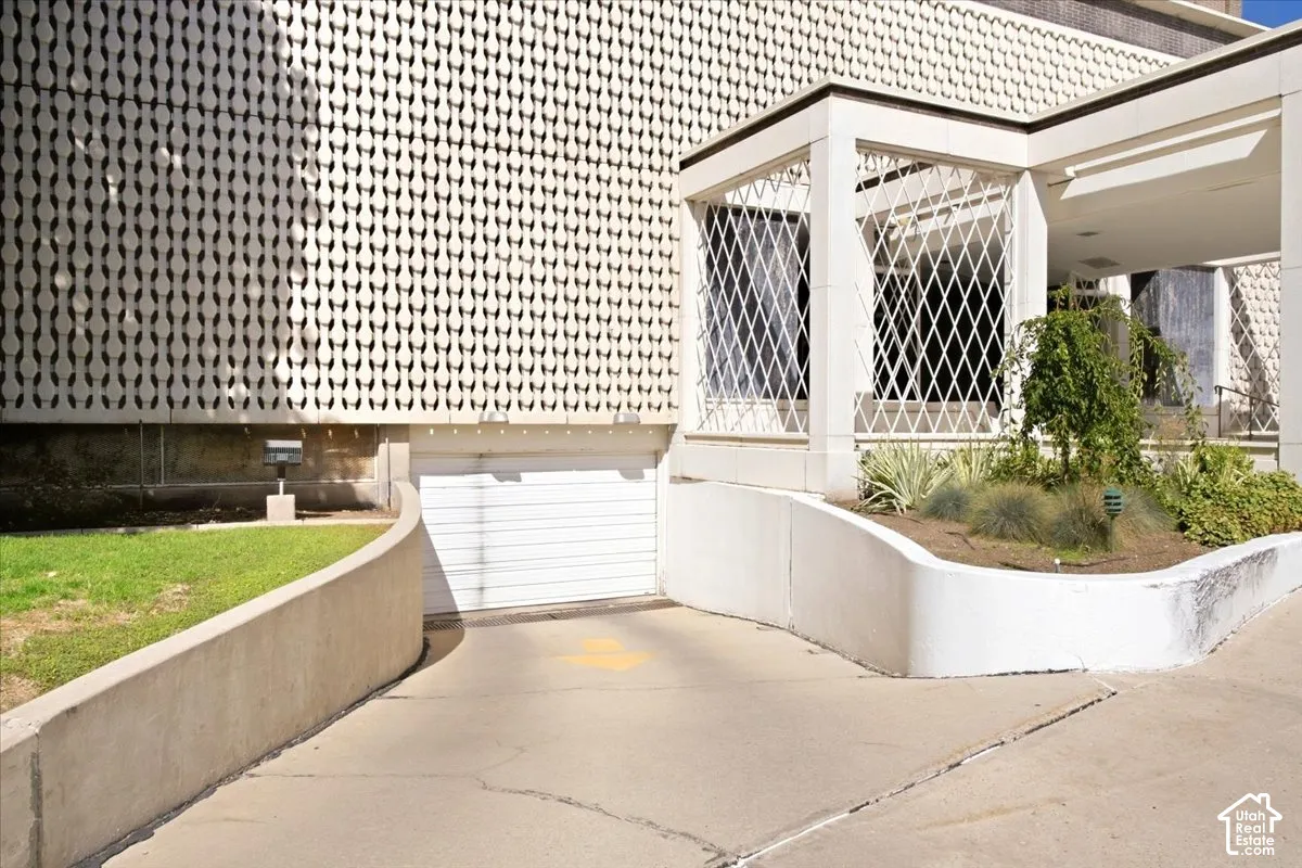 Concrete driveway leading to a garage door, featuring a decorative 'breeze block' exterior wall cover