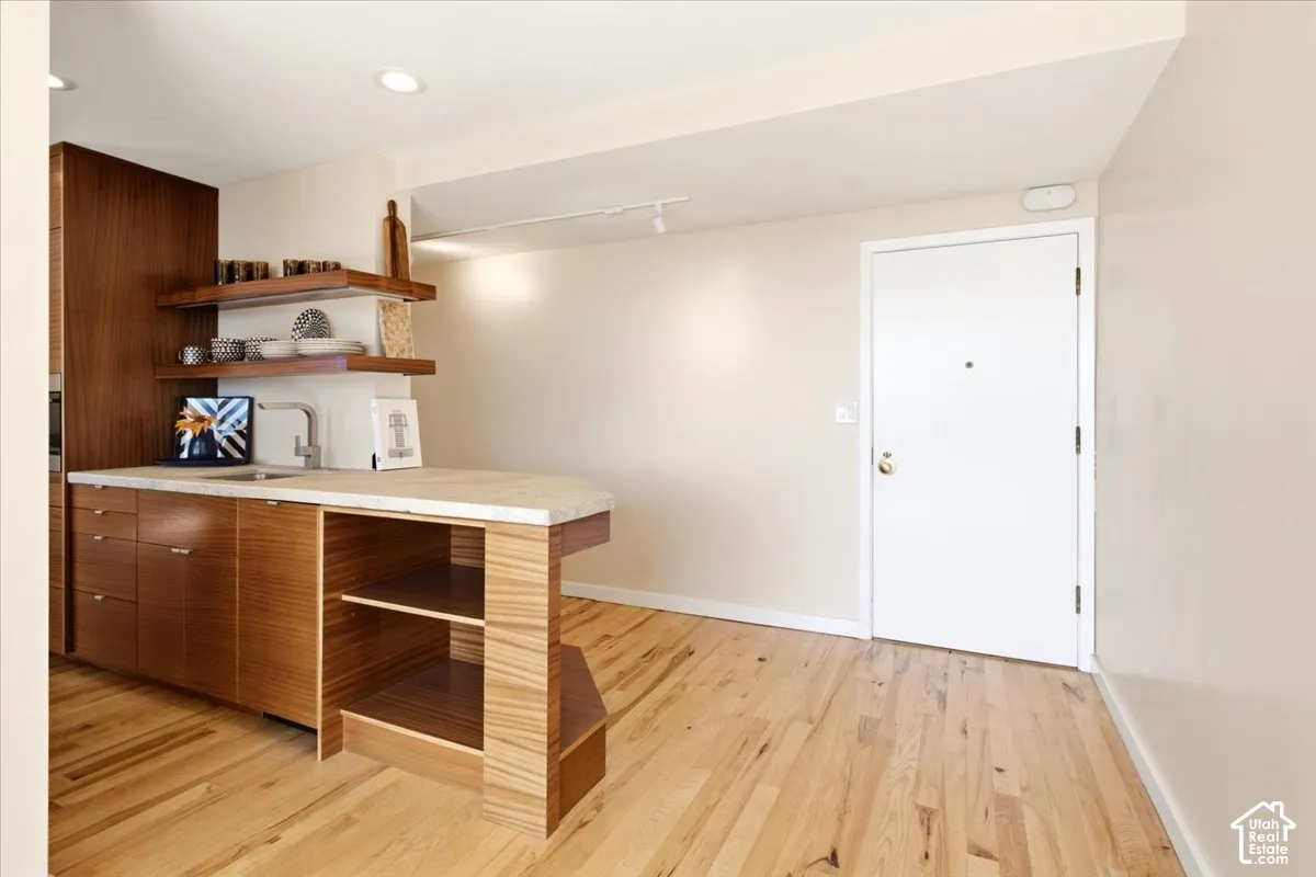 Wood-finish flooring, recessed lighting, built-in open shelving, under-mount sink, and a built-in kitchen island with integrated shelving