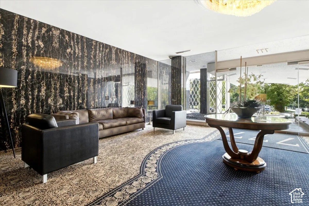 Polished stone wall with gold veining, recessed ceiling lighting, and large glass entry doors