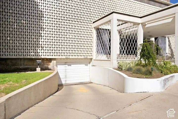 Concrete driveway leading to a garage door, featuring a decorative 'breeze block' exterior wall cover