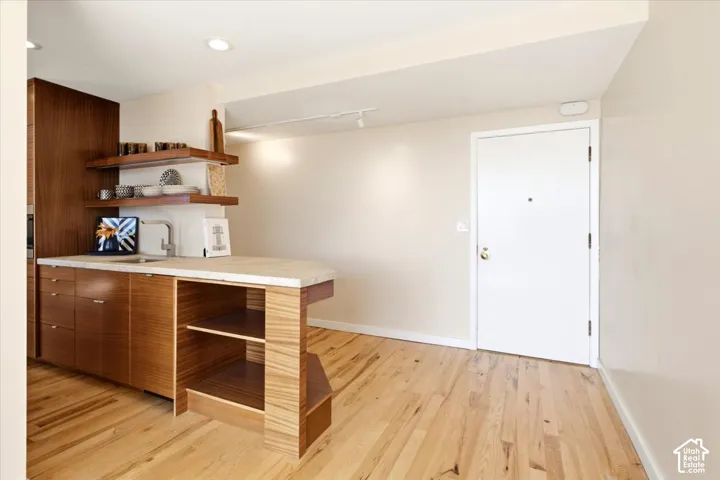 Wood-finish flooring, recessed lighting, built-in open shelving, under-mount sink, and a built-in kitchen island with integrated shelving