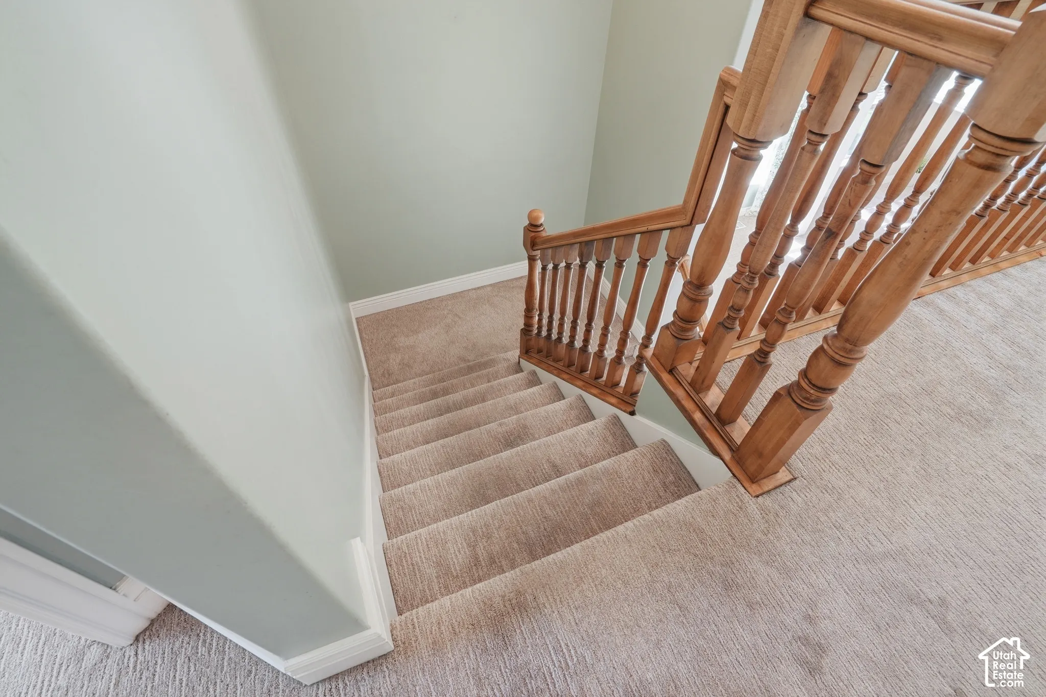Staircase with carpeted treads and risers, featuring a wood balustrade and handrail