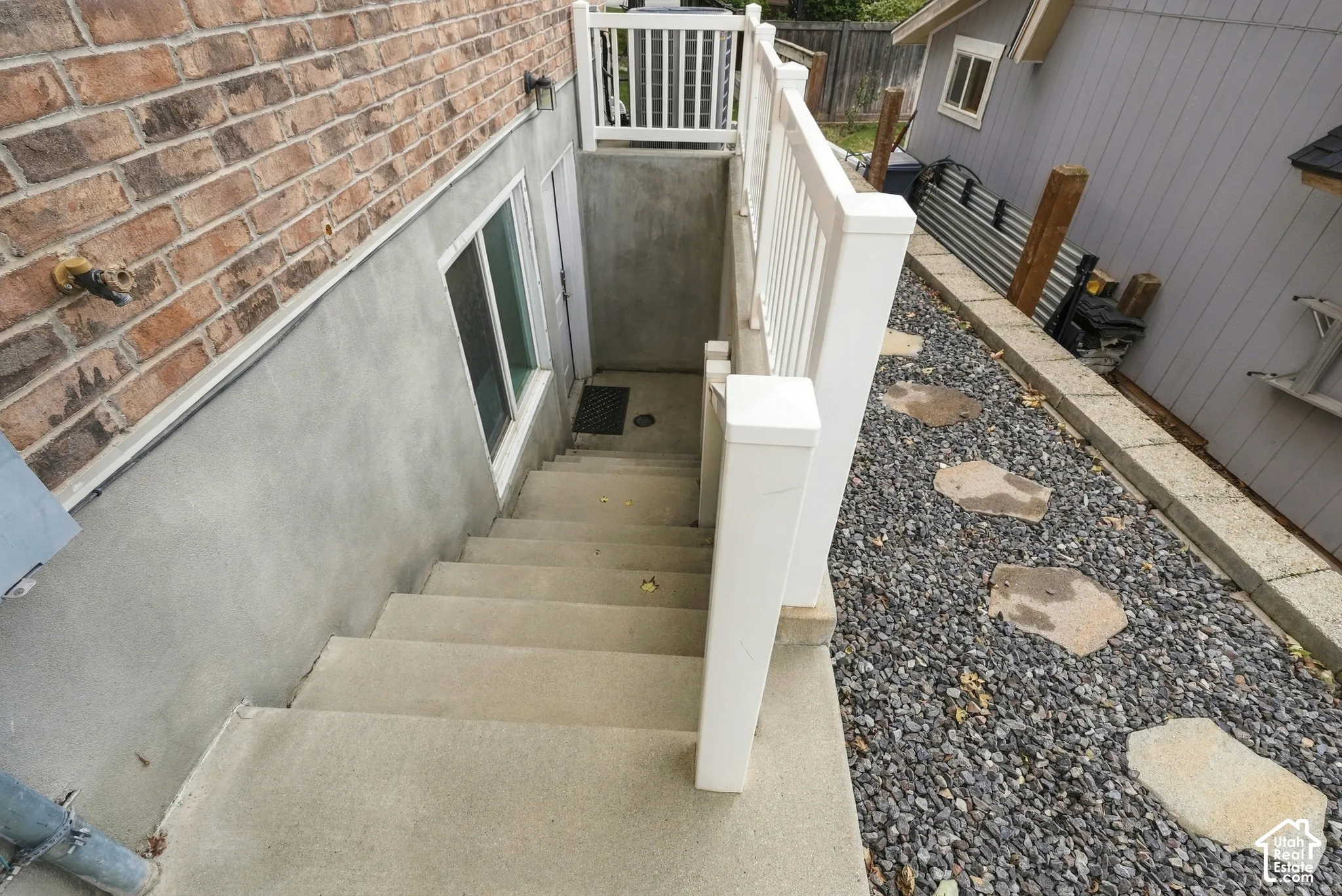 Concrete exterior stairs with white railing leading to a lower-level entry