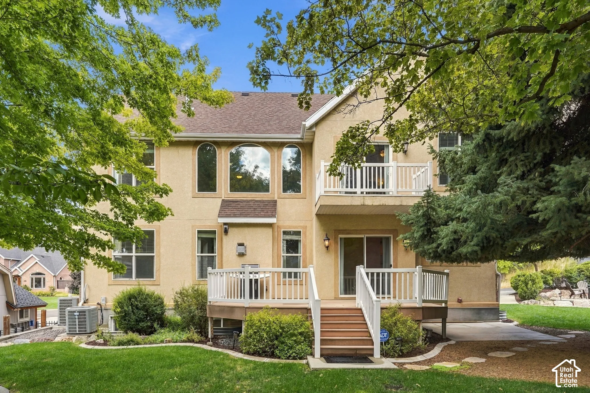 Stucco exterior with a multi-level deck, upper-level balcony, and arch-top windows