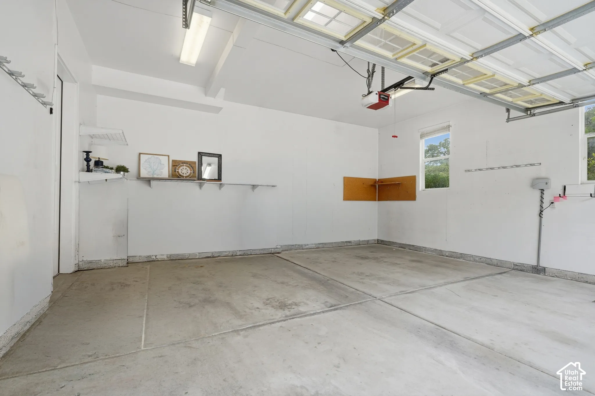 Concrete flooring with overhead lighting, built-in shelving, and two windows
