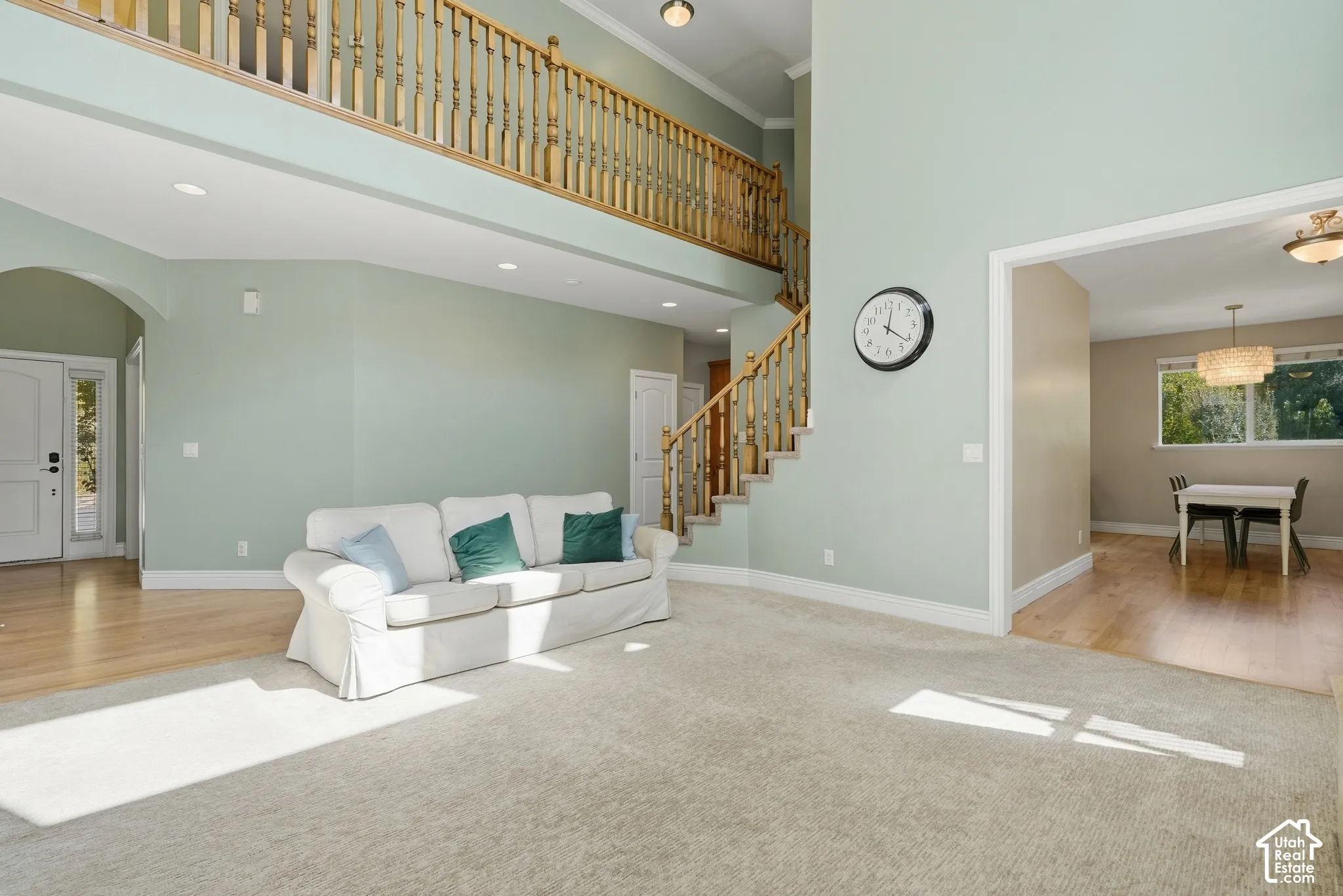Two-story entry with a wood baluster staircase, upper-level landing, recessed lighting, and a defined dining area with a chandelier
