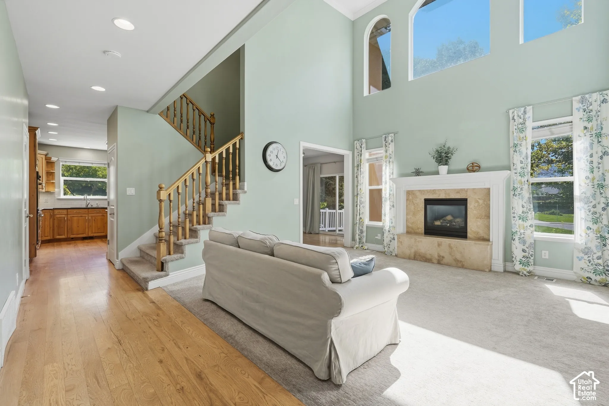 Two-story living area with high ceilings, featuring a gas fireplace with stone surround and mantle, and wood-finish flooring