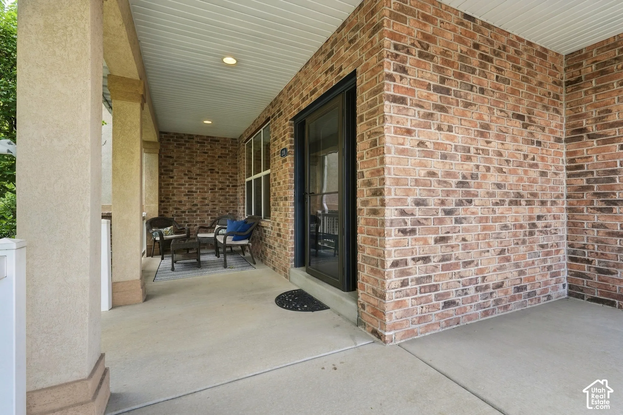 Brick exterior with a covered porch, stucco-finished columns, and a recessed entry