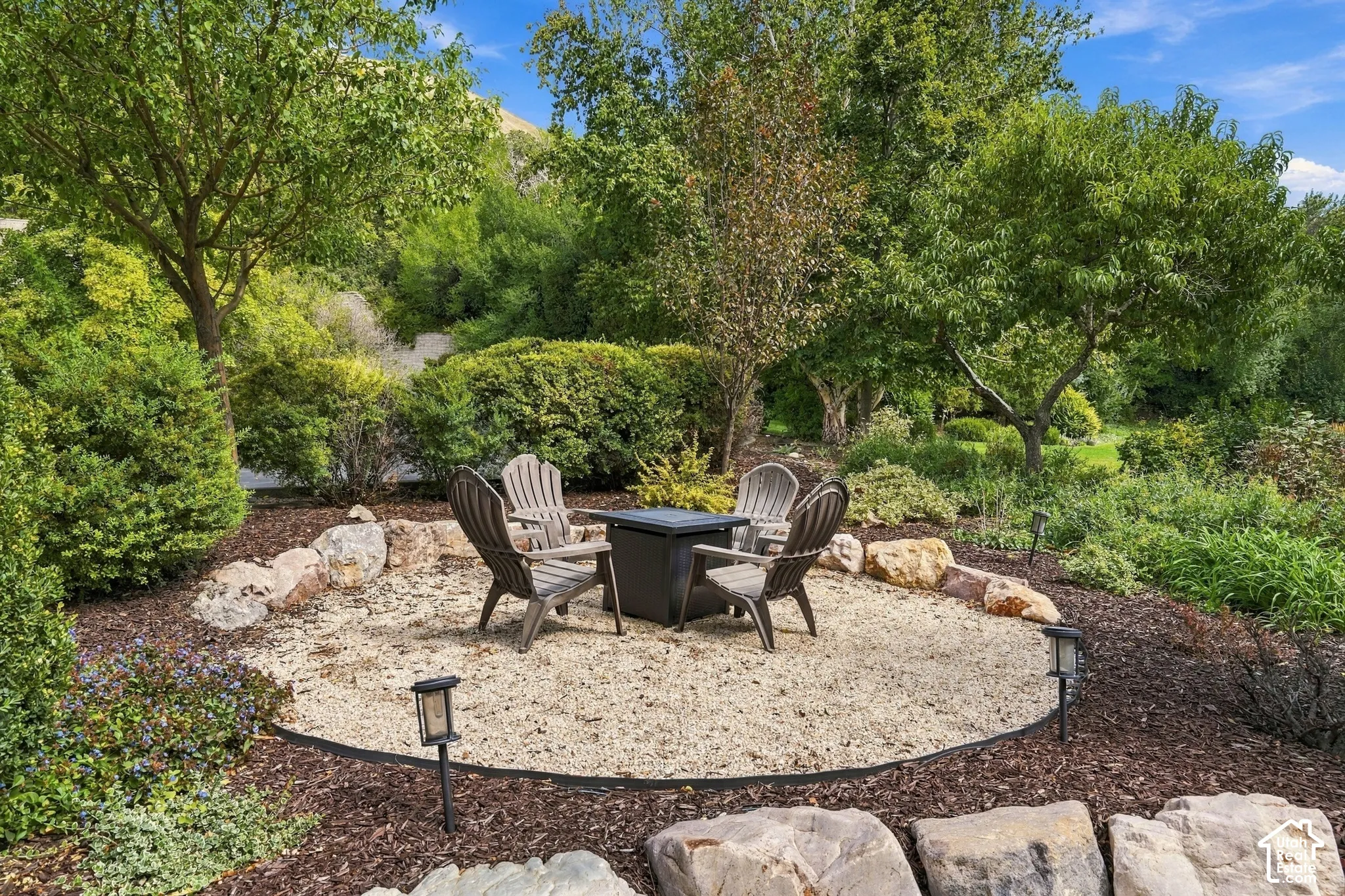 Landscaped outdoor area featuring a gravel seating zone, natural rock accents, and established trees