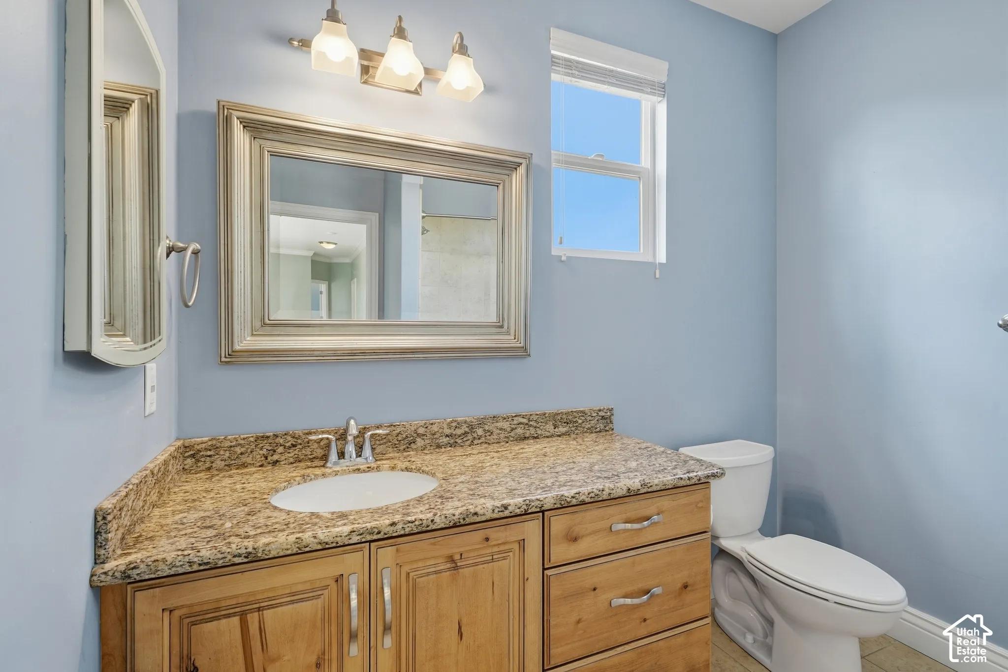 Vanity with stone-finish countertop, undermount sink, and wood-finish cabinetry