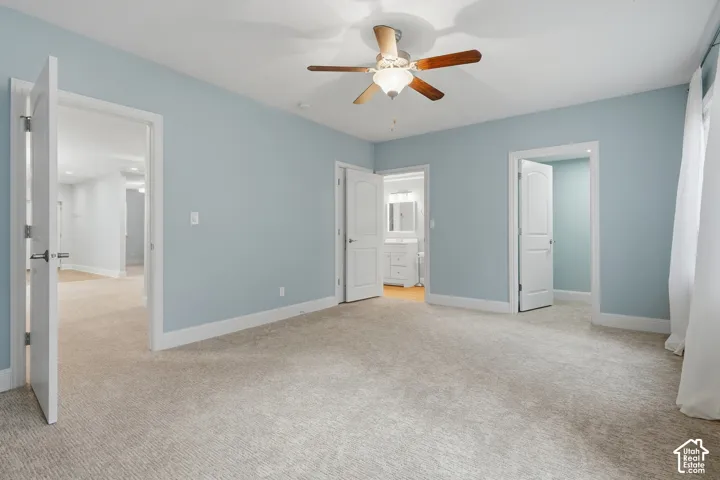 Ceiling fan with light fixture, light blue wall paint, white trim throughout, textured carpet flooring, white door with dark hardware