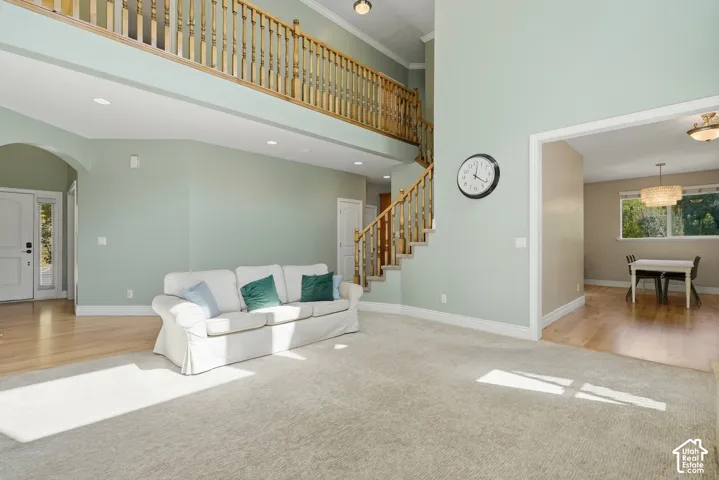 Two-story entry with a wood baluster staircase, upper-level landing, recessed lighting, and a defined dining area with a chandelier