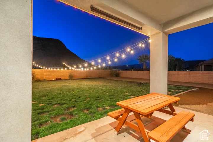 Covered patio with concrete flooring, string lighting, and a lawn area