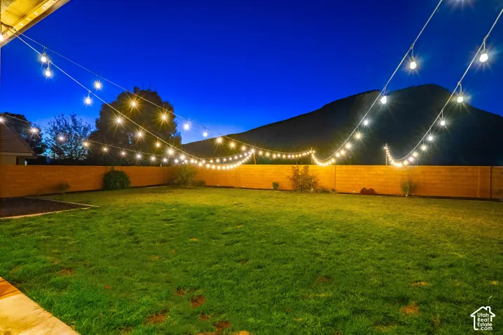 Expansive backyard featuring a manicured lawn, string lighting, and a block fence