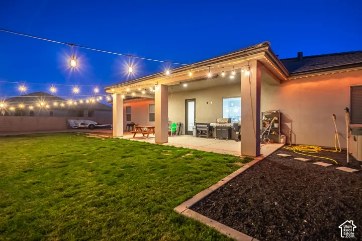 Expansive backyard with a covered patio, concrete paving, and a manicured lawn area