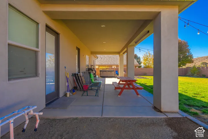 Expansive covered patio with recessed lighting and concrete flooring overlooking a manicured lawn