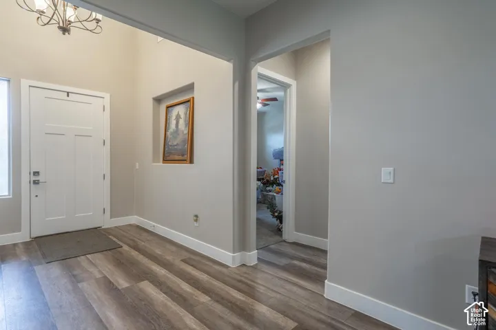 Wood-finish flooring with crisp white baseboards, light gray wall paint, and recessed wall niche