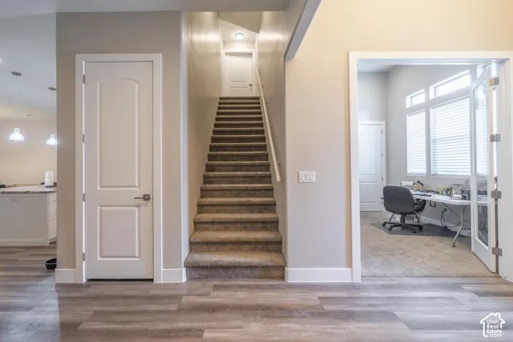Wood-finish flooring, carpeted staircase, recessed lighting, and a room with French doors and transom windows