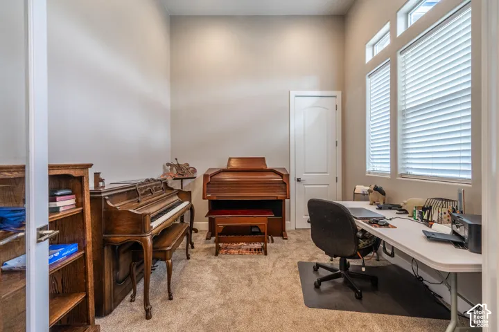 Carpeted room featuring a white paneled door, high ceilings, and large windows with blinds