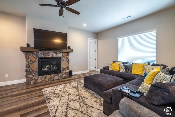 Stone-faced fireplace with a wood mantel, wood-finish flooring, recessed lighting, and a ceiling fan