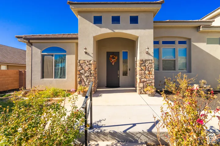 Stucco exterior with stone accents, arched entryway, and diverse window designs