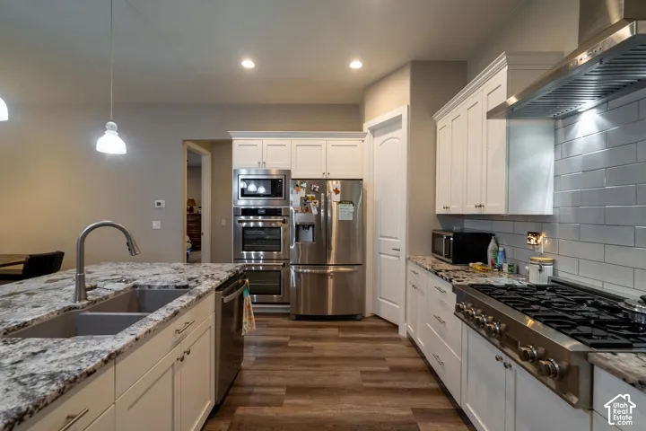 Gourmet kitchen featuring stainless steel appliances, white cabinetry, granite countertops, and wood-finish flooring