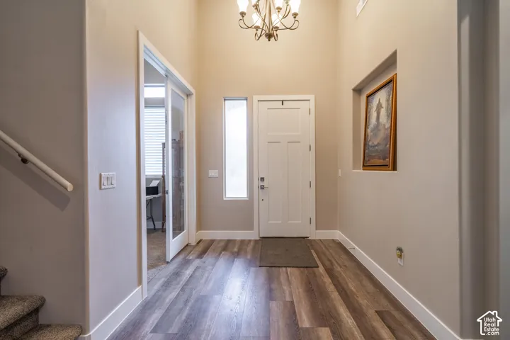 Entryway featuring wood-finish flooring, a contemporary chandelier, a white craftsman-style door, and a transom window
