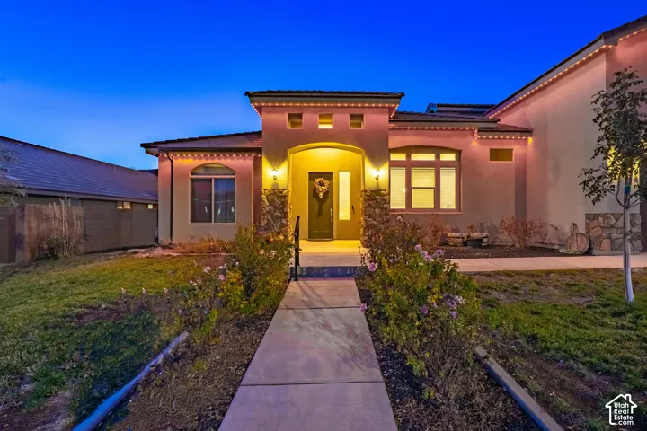 Stucco exterior with stone accents, covered entryway, and a concrete pathway
