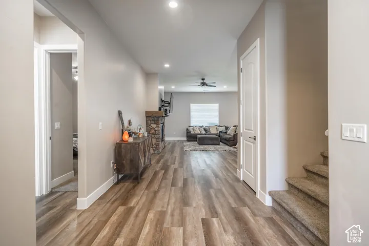 Wood-finish flooring throughout the main living areas, recessed ceiling lighting, and a stone-clad fireplace with a wood mantel