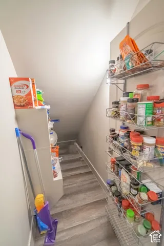 Built-in wire shelving, sloped ceiling, wood-finish flooring, and white walls