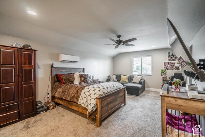 Carpeted flooring, vaulted ceiling, recessed lighting, ceiling fan, and wall-mounted air conditioning unit