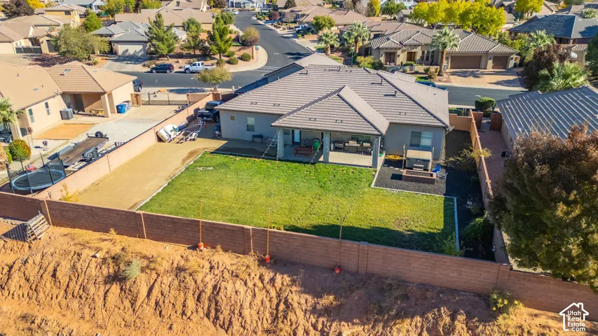 Expansive backyard featuring a manicured lawn, covered patio, surrounding privacy fencing, and a dedicated gravel area